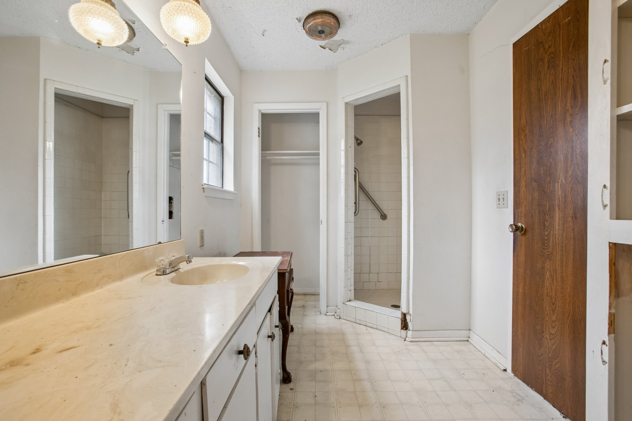 406 Monkey Road Elgin, TX 78621 - Photo 18 of 39 Bathroom featuring a vanity with an integrated sink, a window, a built-in shower stall with white tile, a closet, and built-in shelving