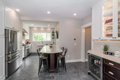 a kitchen with refrigerator a sink and chairs