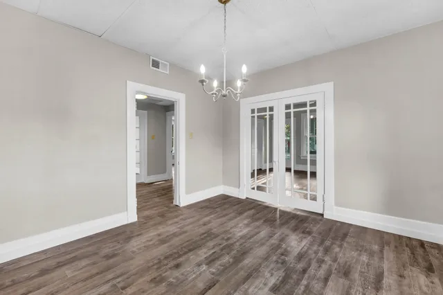 a view of an empty room with wooden floor and a kitchen