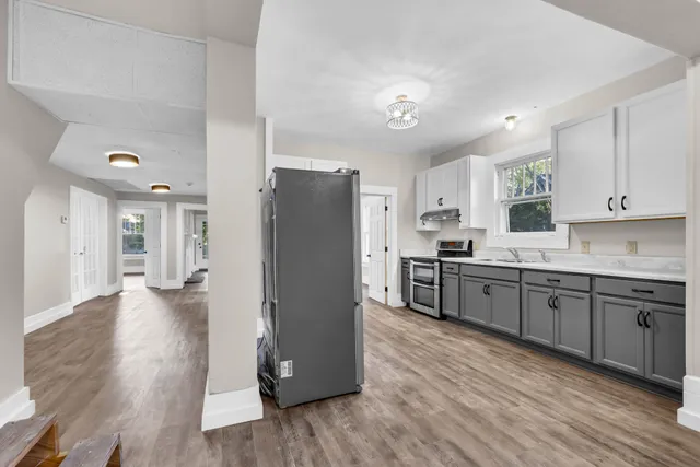 a kitchen with granite countertop a refrigerator stove top oven and cabinets