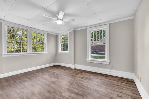 a view of an empty room with a window and wooden floor
