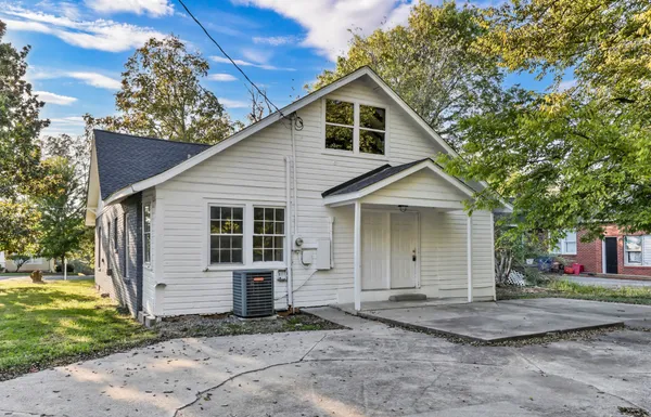 a view of a house with a yard and large tree
