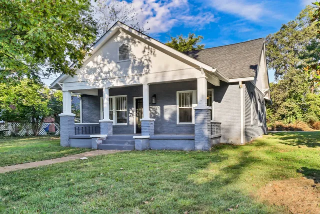 a view of a house with a yard and large tree