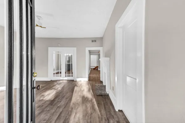 a view of a hallway with wooden floor and a bathroom