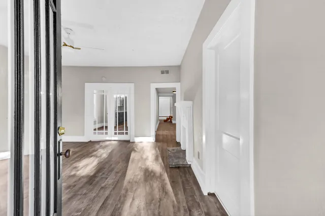 a view of a hallway with wooden floor and a bathroom