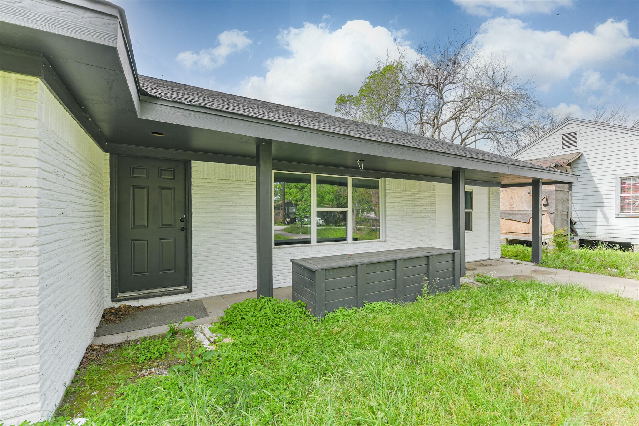 209 Leago Street Houston, TX 77022 - Photo 22 of 24 This photo shows a cozy, single-story home with a covered front porch. The exterior features white brick with dark trim, a grassy front yard, and a simple, inviting entrance.