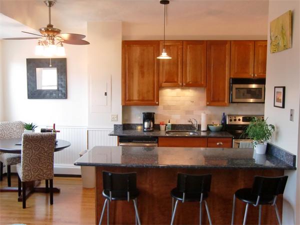 a kitchen with stainless steel appliances granite countertop a table chairs in it and wooden floors