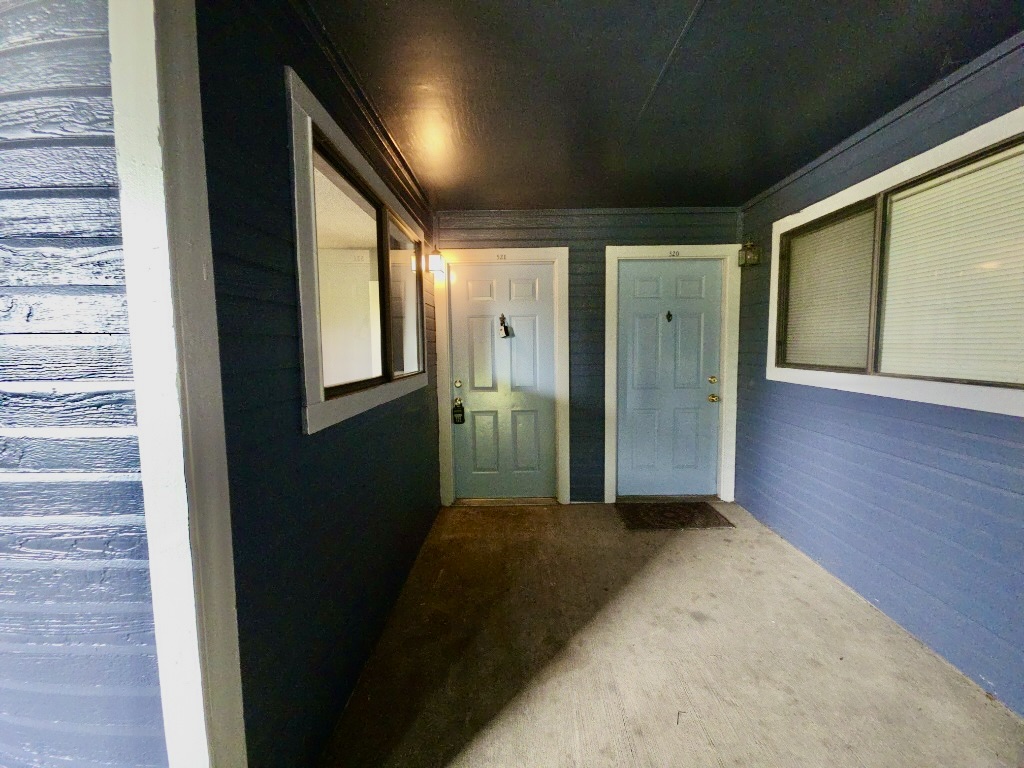 2500 Burleson Road, Unit 521 Austin, TX 78741 - Photo 2 of 20 Covered entry area featuring board and batten siding, two panel doors with overhead numbers, and a concrete walkway