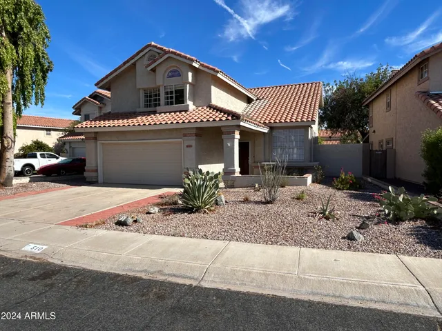 a front view of a house with plants and parking