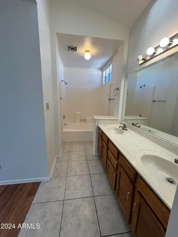 a spacious bathroom with a double vanity sink a toilet a mirror and a bathtub