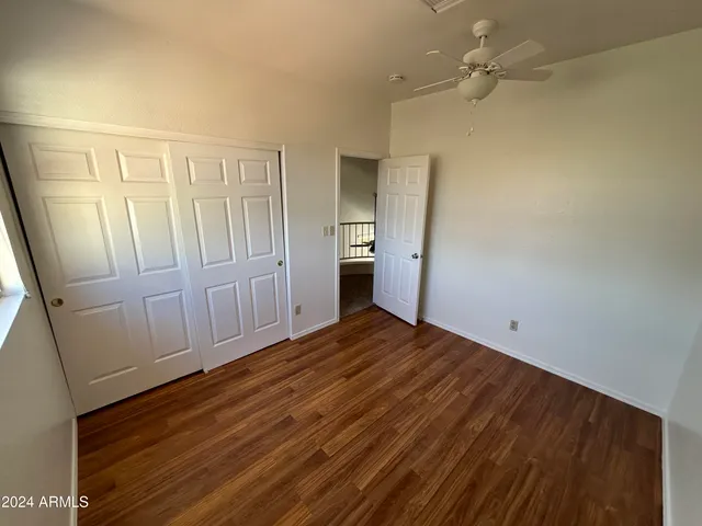 a view of empty room with wooden floor and fan
