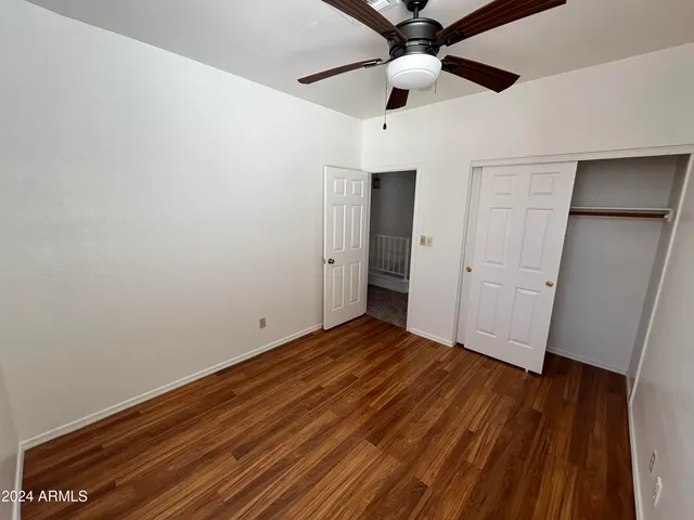 an empty room with wooden floor closet and ceiling fan