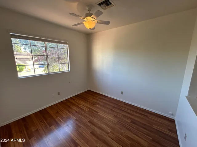 a view of empty room with wooden floor and fan