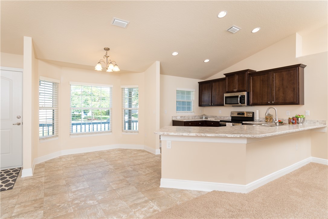 1361 Seahouse Street Sebastian, FL 32958 - Photo 4 of 13 a large kitchen with kitchen island granite countertop a large window and a sink