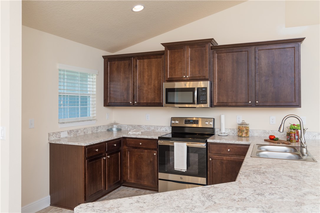 1361 Seahouse Street Sebastian, FL 32958 - Photo 5 of 13 a kitchen with stainless steel appliances granite countertop wooden cabinets a stove top oven a sink and dishwasher