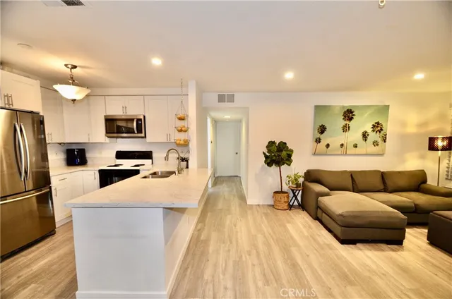 a living room with stainless steel appliances furniture and a view of kitchen