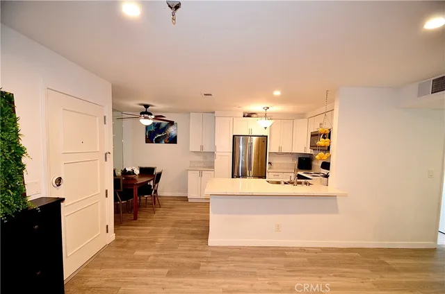 a large white kitchen with a refrigerator a stove and a dining table with wooden floor