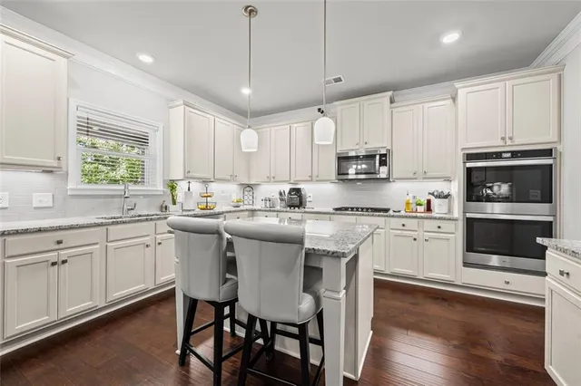 a kitchen with stainless steel appliances granite countertop a stove a sink a microwave a center island and a window