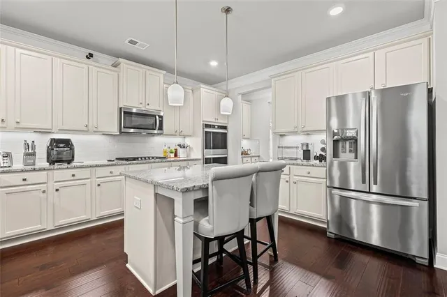 a kitchen with stainless steel appliances granite countertop a refrigerator a stove a sink a stove a dining table and chairs with wooden floor