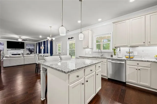 a kitchen with stainless steel appliances kitchen island granite countertop a stove top oven a sink a dining table and chairs with wooden floor