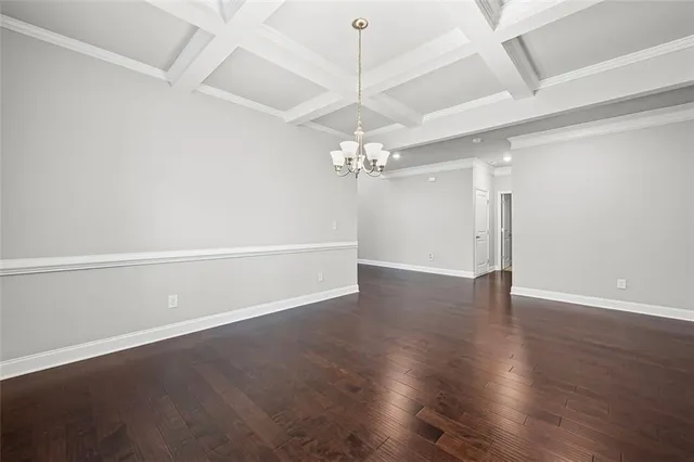 an empty room with wooden floor chandelier and windows