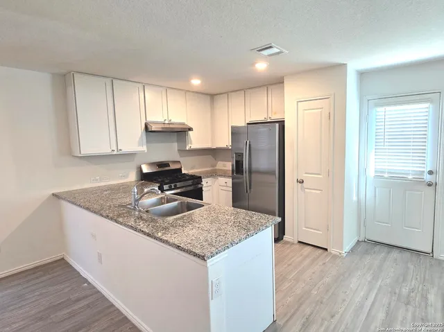 a kitchen with kitchen island granite countertop a sink stove and refrigerator