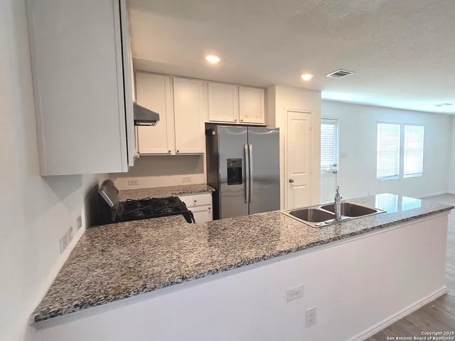 a kitchen with kitchen island granite countertop a sink a refrigerator and a counter top space