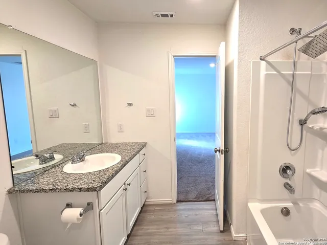 a bathroom with a granite countertop sink and a mirror