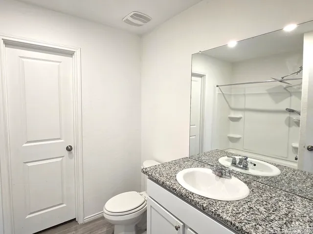 a bathroom with a granite countertop sink toilet a mirror and shower
