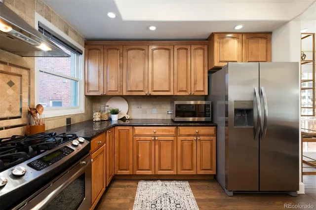 a kitchen with stainless steel appliances granite countertop a refrigerator a sink and a stove