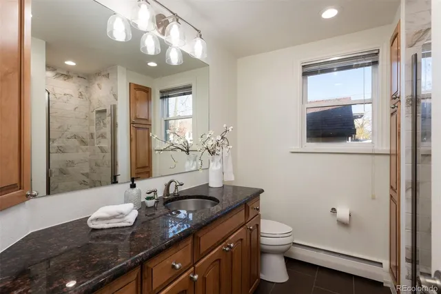 a bathroom with a granite countertop sink a toilet and a mirror