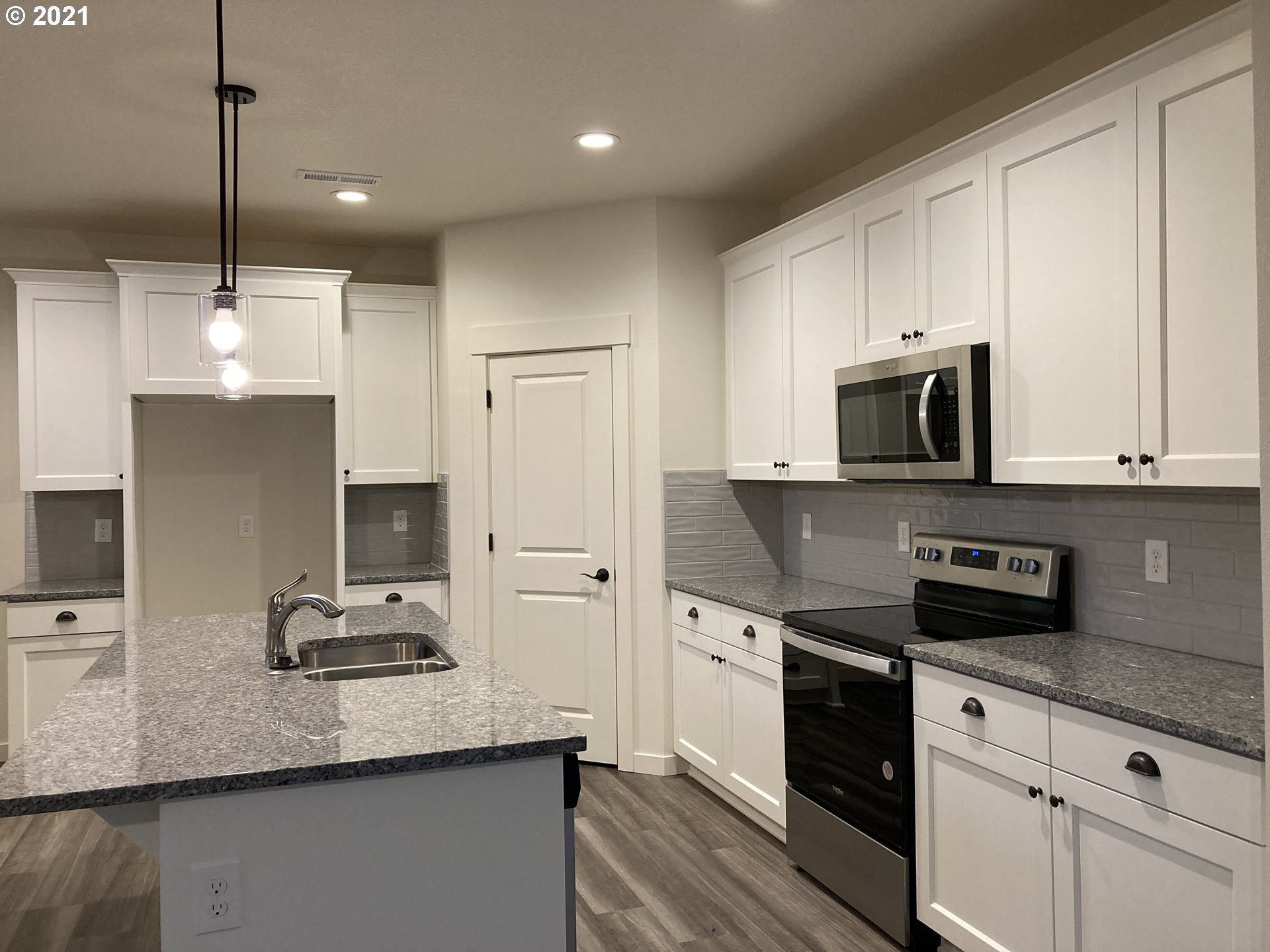 7023 South Ridge Way Ridgefield, WA 98642 - Photo 3 of 13 a kitchen with a sink stainless steel appliances and white cabinets