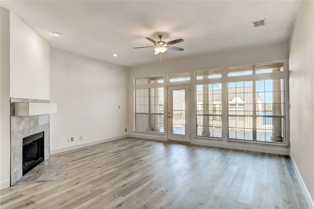 a view of an empty room with wooden floor and a fireplace