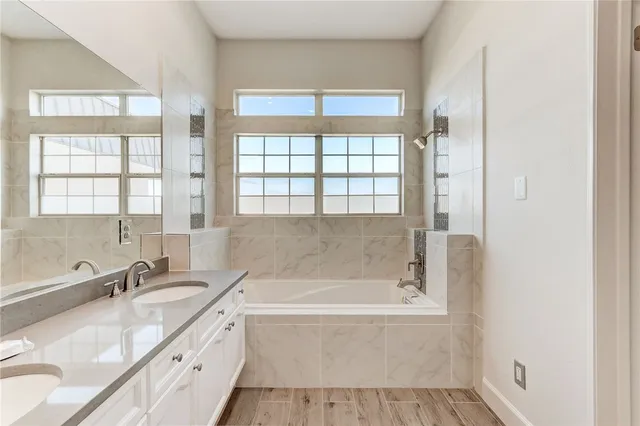 a bathroom with a granite countertop tub sink and mirror