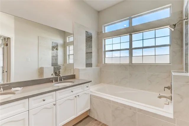 a bathroom with a granite countertop sink and a bathtub