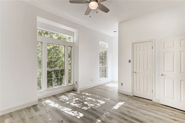 en empty room with windows and ceiling fan