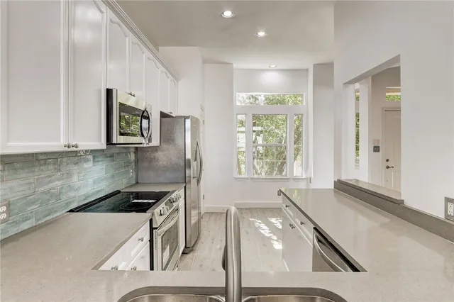 a kitchen with stainless steel appliances granite countertop a sink a stove a refrigerator a counter top space and cabinets