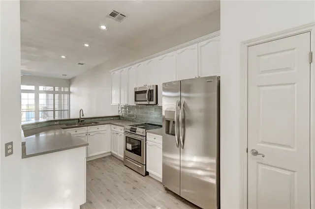 a kitchen with stainless steel appliances granite countertop a refrigerator a stove and a sink