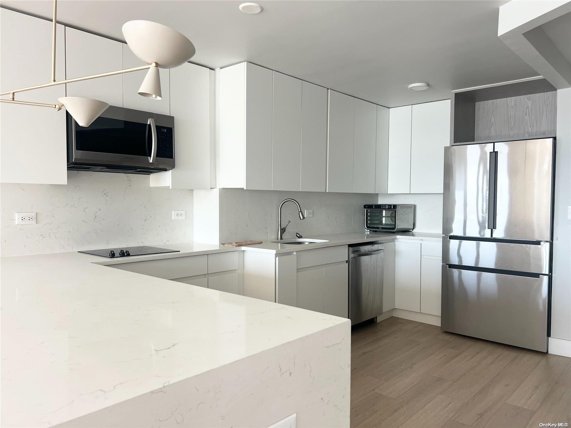 200 Rector Place, Unit 35E Manhattan, NY 10280 - Photo 6 of 33 a kitchen with stainless steel appliances a refrigerator stove a sink and a microwave