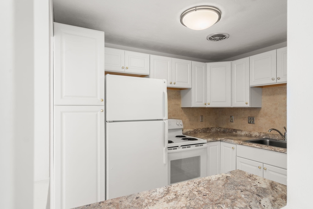 1325 Worcester Road, Unit A11 Framingham, MA 01701 - Photo 6 of 18 a kitchen with a refrigerator sink and cabinets