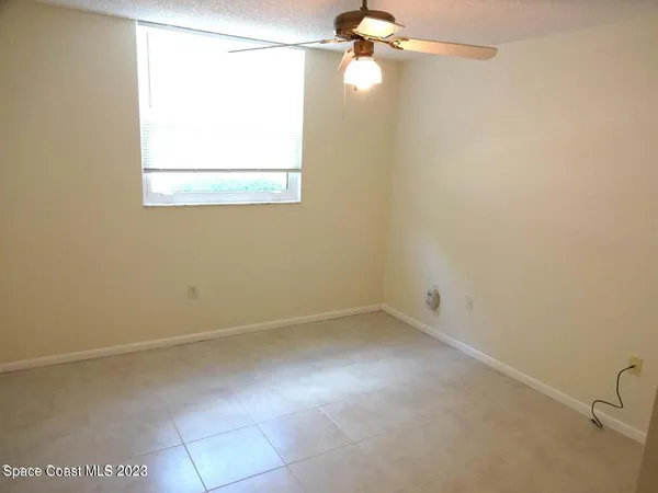 an empty room with a window and a fan