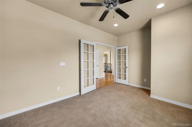 an empty room with a ceiling fan and carpet