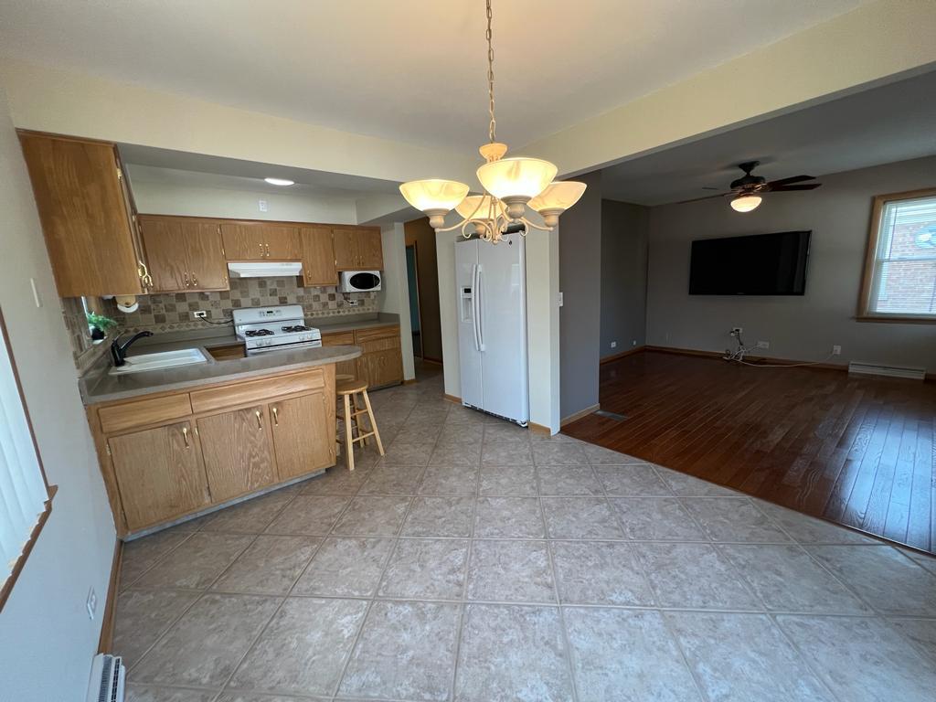 4031 Custer Avenue Lyons, IL 60534 - Photo 13 of 38 a kitchen that has a lot of cabinets in it and wooden floor