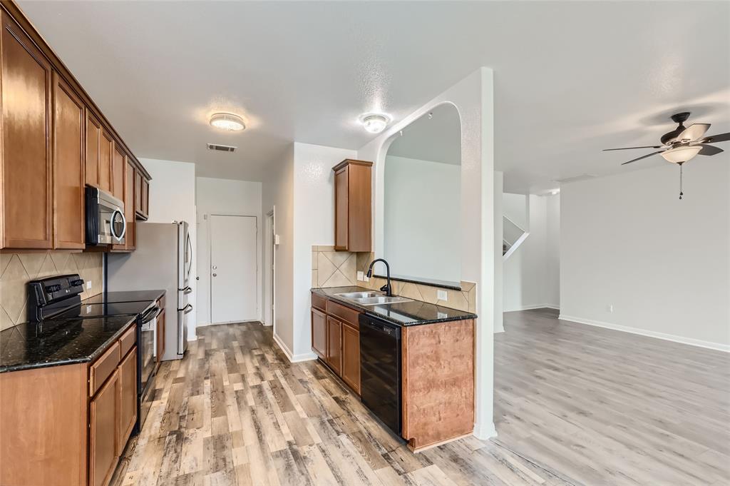 131 Lavaca Loop Hutto, TX 78634 - Photo 5 of 29 A contemporary kitchen showcasing dark granite counters and sleek stainless steel appliances.
