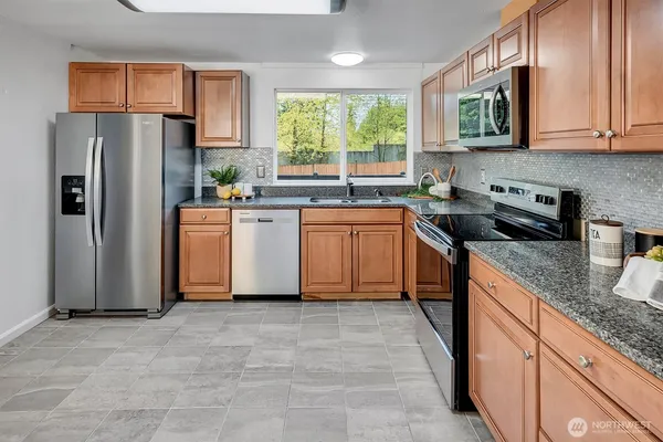 a kitchen with stainless steel appliances granite countertop a refrigerator sink and stove