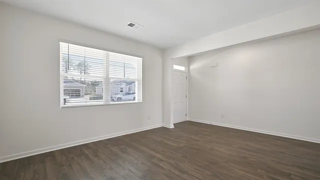 a view of an empty room with wooden floor and a window