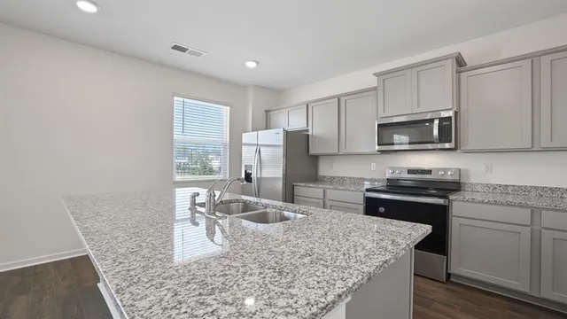 a kitchen with stainless steel appliances granite countertop a sink stove microwave and refrigerator