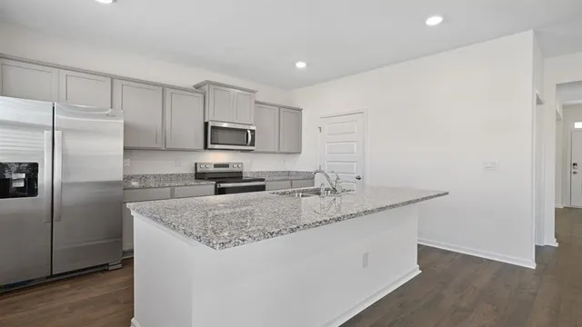 a kitchen with kitchen island granite countertop a sink stove microwave and refrigerator