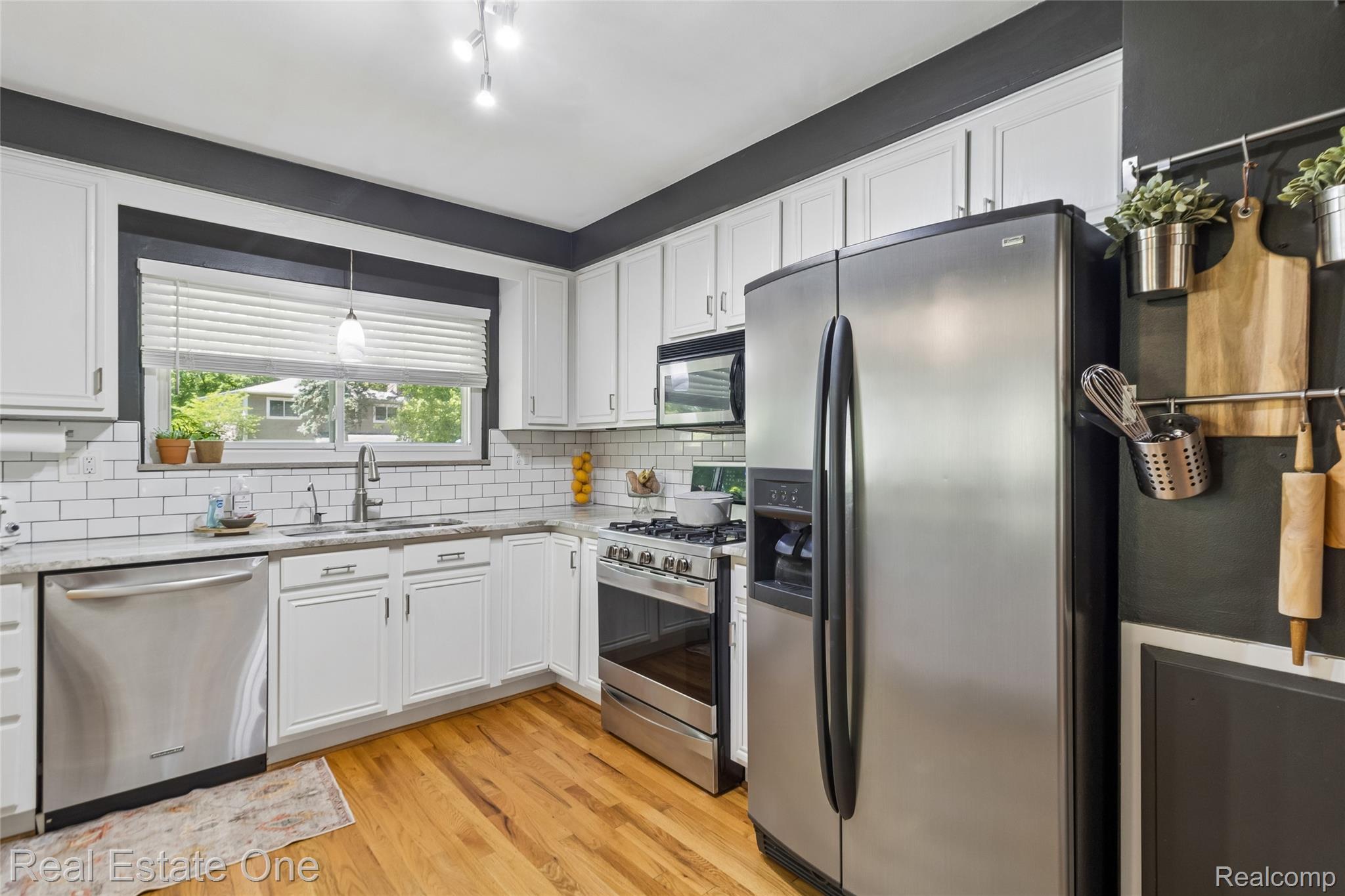 2189 Devonshire Road Bloomfield Hills, MI 48302 - Photo 13 of 50 Kitchen featuring white shaker cabinetry, stainless steel appliances, a subway tile backsplash, light-colored countertops, and wood-finish flooring