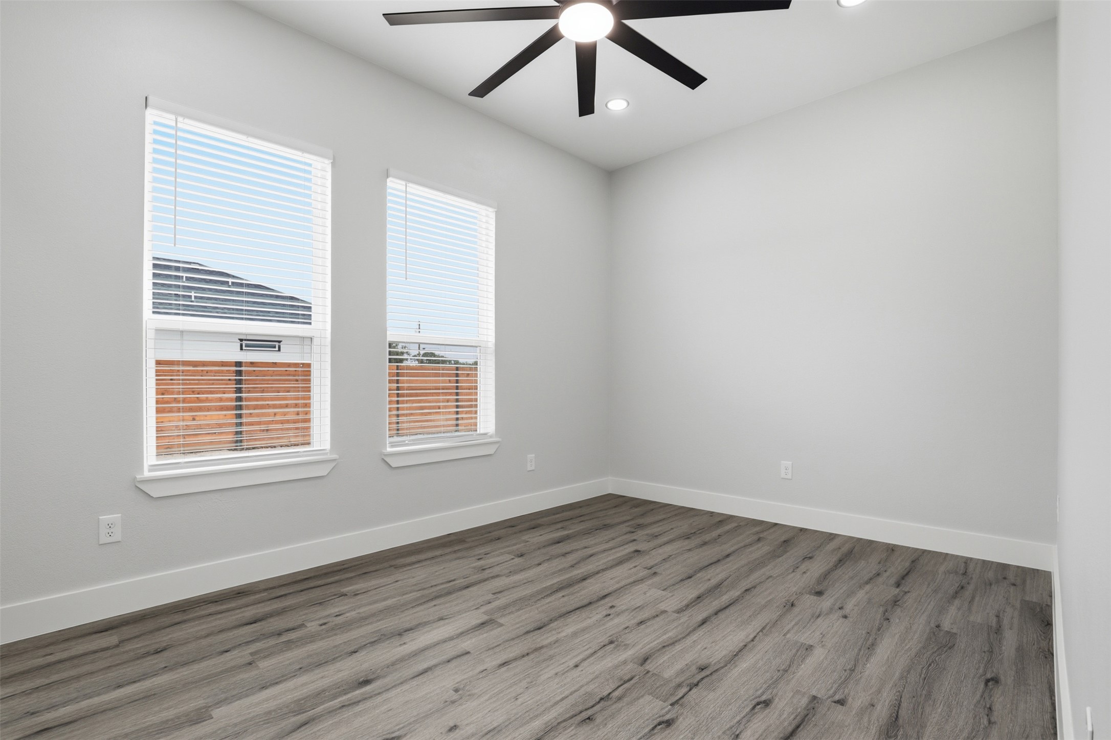 123 Los Robles Road Elgin, TX 78621 - Photo 17 of 21 Room featuring wood-finish flooring, light gray walls, and two windows with blinds